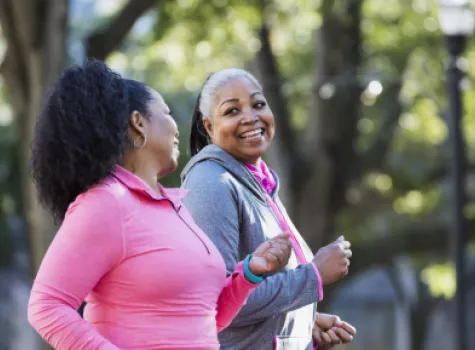 Two Black Women Smiling at Each Other While Enjoying a Power Walk Outside