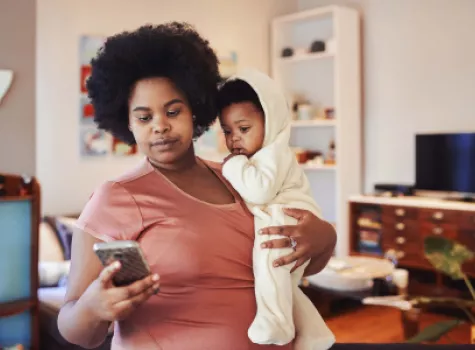 Black Female Holding Baby and Checking iPhone