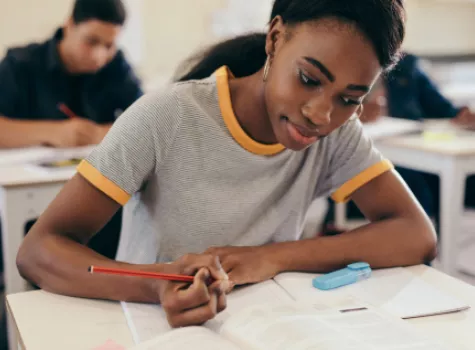 Black Student Sitting at Classroom Desk Doing Coursework