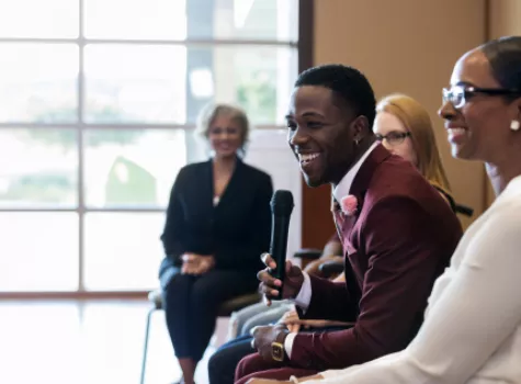 Smiling Black Man Holding Microphone in Group Setting