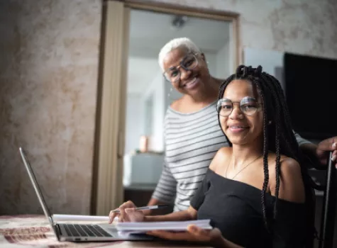 Black Female Student and Supportive Person Smiling at Camera - Indoors