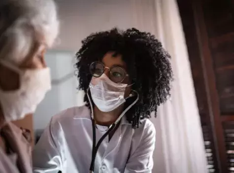 Masked Doctor Using Stethoscope with Patient