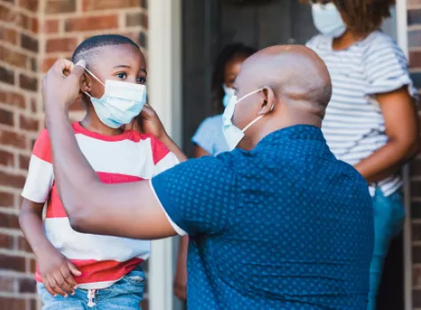 Black Man Helping a Child Put on a Mask