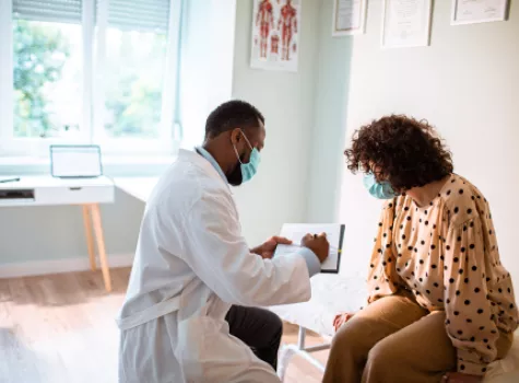 Masked Doctor and Patient Reviewing Paperwork