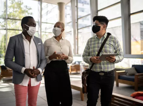 Three Adults Speaking While Walking in an Office - Smiling