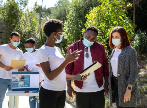 Group of Young Adults - Working Together and Looking at Paper Pad - Outside