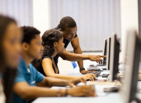 Young Black Man Helping A Female at a Computer - Classroom Setting