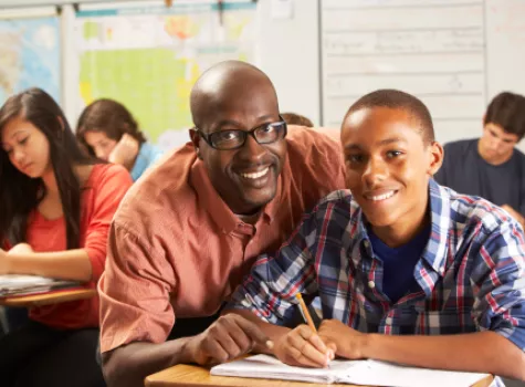 Teacher and Student Smiling at Camera inside Clasroom Setting