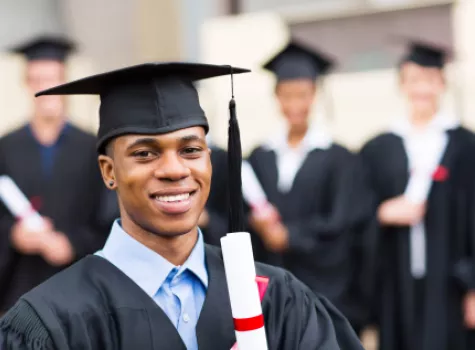 Black Male Graduate Smiling at Camera and Holding Diploma