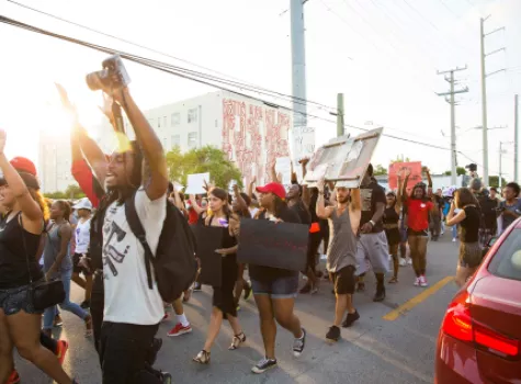 Young Adults Protesting on a Street with Arms Raised