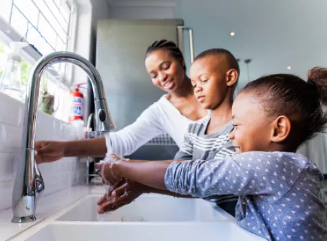 Black Mother with Two Children in Front of Kitchen Sink - Smiling