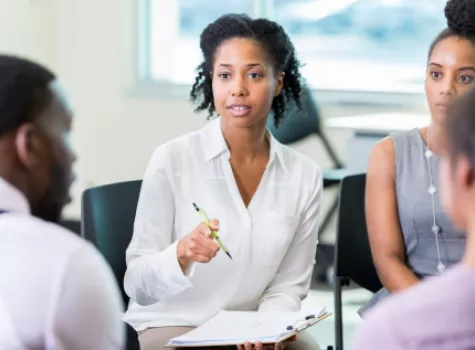 Female Professional Speaking to a Seated Group of People