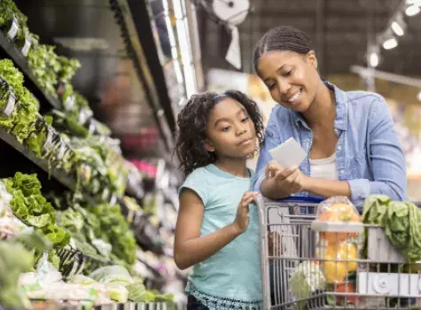 Mother and Child with Shopping Cart Reviewing List in Grocery Store