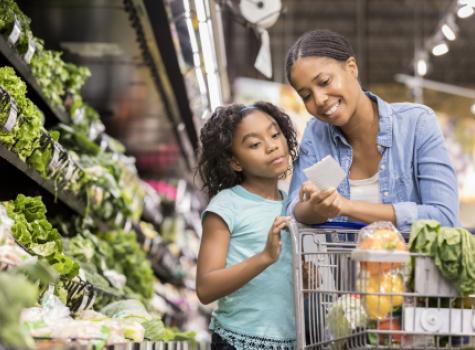 Mother and Child with Shopping Cart Reviewing List in Grocery Store