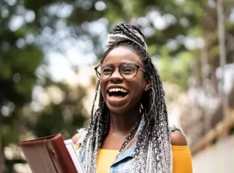 Joyous Young Black Woman Holding Books - Outdoors