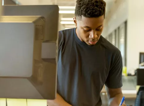 Young Black Male - Solo - standing working at computer - classroom setting