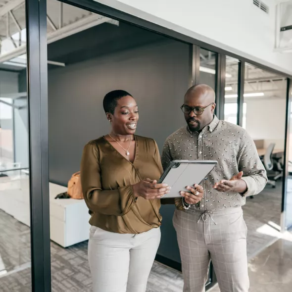 Businesspeople Collaborating Over Tablet In Office Setting